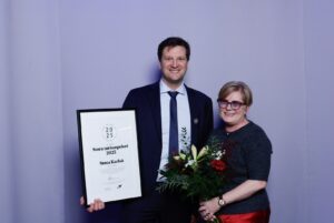 kvinna och man mottar Stora turismpriset 2025. Står bredvid varandra med diplom och blommor i händerna